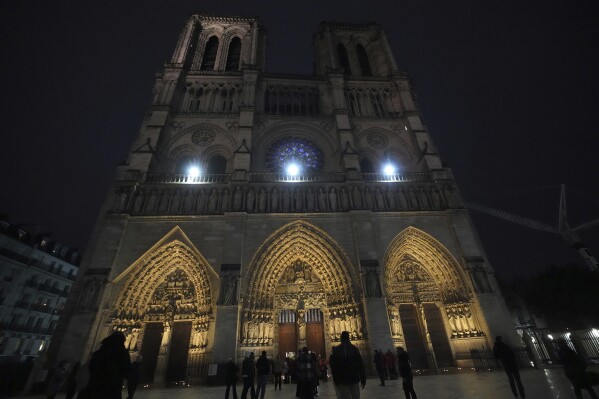 People head to Notre Dame Cathedral for the the first mass opened to the public, Sunday, Dec. 8, 2024 in Paris. (AP Photo/Michel Euler)