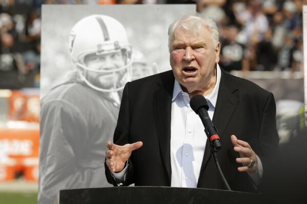 FILE - Former Oakland Raiders head coach John Madden speaks about former quarterback Ken Stabler, pictured at rear, during a ceremony honoring Stabler at halftime of an NFL football game between the Raiders and the Cincinnati Bengals in Oakland, Calif., on Sept. 13, 2015. The NFL is making that a lasting tribute by honoring the late broadcaster by launching the “John Madden Thanksgiving Celebration” to begin on the first Thanksgiving following his death last December. (AP Photo/Ben Margot, File)