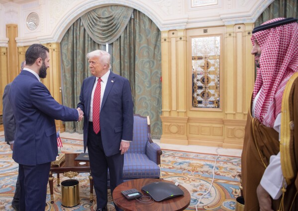 In this photo released by the Saudi Royal Palace, Syria's interim President Ahmad al-Sharaa, left, shakes hands with President Donald Trump, centre, in Riyadh, Saudi Arabia, Wednesday, May 14, 2025. At right is Saudi Crown Prince Mohammed bin Salman.(Bandar Aljaloud/Saudi Royal Palace via AP)