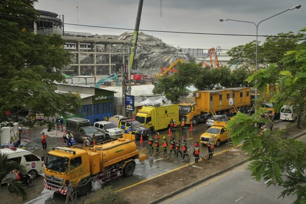 Workers clean and wash the road outside the site of an under construction high-rise building that collapsed after an earthquake in Bangkok, Thailand, Thursday, April, 3, 2025. (AP Photo/Manish Swarup)