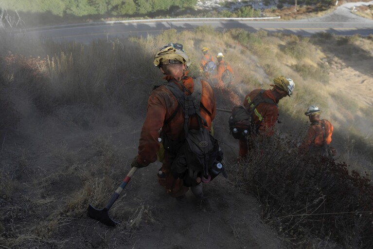 FILE - *Inmate firefighter David Clary, 41, with the Mount Gleason Conservation Camp 16, walks down a steep hill after eight hours of fighting a wildfire in the Angeles National Forest near Azusa, Calif., Saturday, Sept. 5, 2009. (AP Photo/Jae C. Hong, File)
