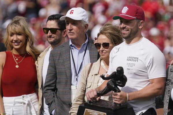 Former Oklahoma quarterback Baker Mayfield poses with his Heisman Trophy and his family at midfield during events for the dedication of a statue of him outside Gaylord Family Memorial Stadium, during halftime of Oklahoma's NCAA college football spring game Saturday, April 23, 2022, in Norman, Okla. (AP Photo/Sue Ogrocki)