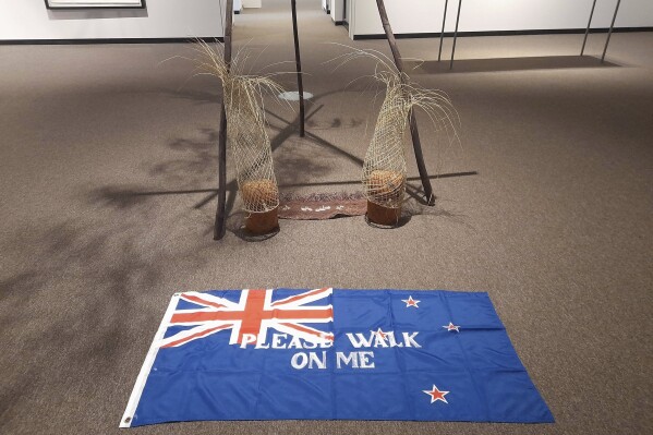 An artwork titled Flagging the Future, a cloth New Zealand flag with the words "please walk on me" stenciled across it by Māori artist Diane Prince, is displayed on the floor on Tuesday, May 27, 2025, at the Suter Art Gallery in Nelson, New Zealand. (Catherine Hubbard/Nelson Mail/STUFF via AP)
