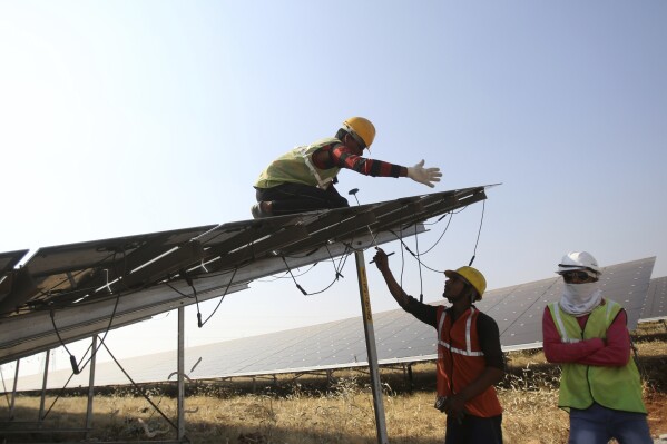 FILE - Workers install solar panels at the Pavagada Solar Park 175 Kilometers north of Bangalore, India, March 1, 2018. Renewable projects have grown steadily in India for years, but a mix of policy decisions, politics and supply chain issues have slowed progress on solar projects in 2023. (AP Photo/Aijaz Rahi, File)