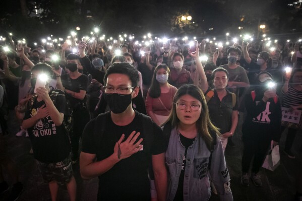 FILE - Demonstrators hold their cellphones aloft as they sing 