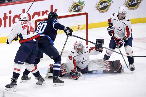 Washington Capitals goaltender Charlie Lindgren (79) covers up the puck after a shot by Winnipeg Jets' Pierre-Luc Dubois (80) during first-period NHL hockey game action in Winnipeg, Manitoba, Sunday, Dec. 11, 2022. (Fred Greenslade/The Canadian Press via AP)
