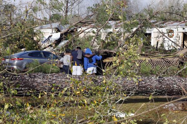 Friends and family pray outside a damaged mobile home, Wednesday, Nov. 30, 2022, in Flatwood, Ala., the day after a severe storm swept through the area. Two people were killed in the Flatwood community just north of the city of Montgomery. (AP Photo/Butch Dill)