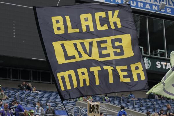 FILE - Seattle Sounders supporters fly a Black Lives Matter flag before an MLS soccer match against Atlanta United, May 23, 2021, in Seattle. On Wednesday, March 29, 2023, German sportswear company Adidas withdrew its opposition to a Black Lives Matter application with the U.S. Trademark Office two days after its filing. On Monday, March 27, Adidas submitted a notice of opposition with the office, saying in the filing that it took issue with Black Lives Matter Global Network Foundation's application to trademark the use of three parallel yellow stripes on various items such as clothing and bags. (AP Photo/Ted S. Warren, File)