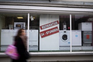 A person walks past a shop offering the repair of electronic equipment and domestic appliances in Berlin, Germany, Friday, Feb. 26, 2021. Companies that sell refrigerators, washers, hairdryers or TVs in the European Union will need to ensure those appliances can be repaired for up to 10 years. The new 'right to repair' comes into force across the 27-nation bloc Monday, March 1, 2021. The posters read: ' Repair - 24 hours'. (AP Photo/Markus Schreiber)