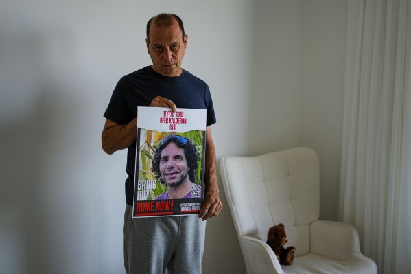Nissan Kalderon poses with a photo of his only brother, Ofer, a hostage held in the Gaza Strip by the Hamas militant group, in Ramat Gan, Israel, Wednesday, March 13, 2024. With each passing day, the relatives of hostages in Gaza face a deepening despair. (AP Photo/Ariel Schalit)