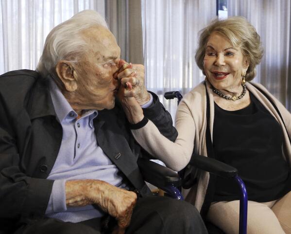 FILE - In this May 4, 2017, file photo, Kirk Douglas kisses his wife Anne's hand, in Los Angeles during a party celebrating his 100th birthday. Anne Douglas, the widow of Kirk Douglas and stepmother of Michael Douglas, died Thursday, April 29, 2021, in California. She was 102. Douglas died at her home in Beverly Hills, according to an obituary provided by spokeswoman Marcia Newberger. No cause of death was given. (AP Photo/Reed Saxon, File)