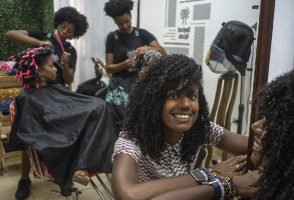 Adriana Heredia poses in front of customers at her Beyond Roots, a private enterprise that includes a clothing store, a beauty salon specializing in afro hair and various other cultural projects, in Havana, Cuba, Tuesday, June 6, 2023. “I am super happy with the new willingness of the United States embassy to pave the way for us in terms of knowledge... that is something we were lacking,” says Adriana Heredia who is part of a small group of entrepreneurs who benefited from a business training program offered by the U.S. embassy in Cuba. (AP Photo/Ramon Espinosa)
