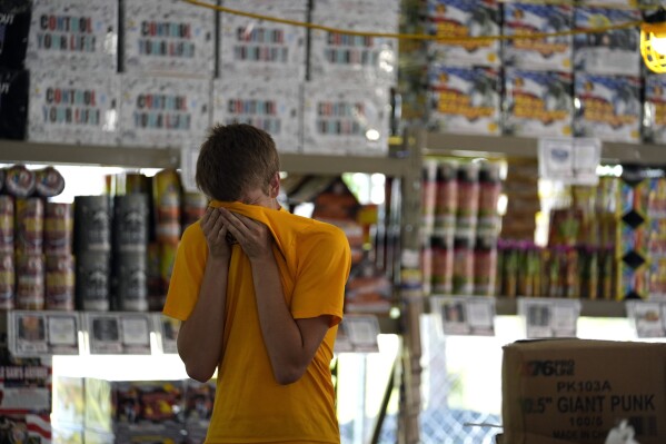 Hunter Van Dyne pauses to wipe sweat from his forehead inside a hot fireworks tent as he works to set up for the opening of Powder Monkey Fireworks, in Weldon Spring, Mo., Monday, June 17, 2024. (AP Photo/Jeff Roberson)