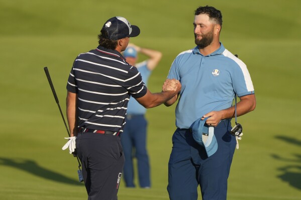 Europe's Jon Rahm shakes hands with United States' Brooks Koepka after the match was tied in their afternoon Fourballs match at the Ryder Cup golf tournament at the Marco Simone Golf Club in Guidonia Montecelio, Italy, Friday, Sept. 29, 2023. (AP Photo/Gregorio Borgia )
