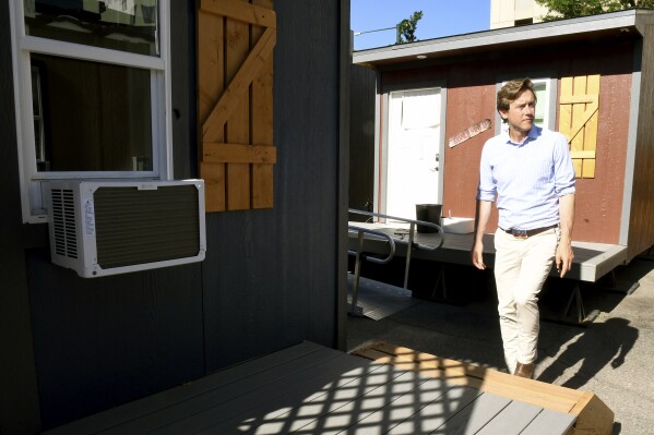 Denver Mayor Mike Johnston tours a micro community in the city on Wednesday, June 5, 2024. The communities consist of small cabin-like structures with a twin bed, desk and closet. The city built three such communities with nearly 160 units total in about six months, at roughly $25,000 per unit to help ease homelessness. (AP Photo/Thomas Peipert)
