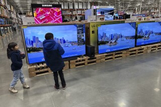 Young shoppers look over a row of large-screen televisions on display in a Costco warehouse Thursday, Dec. 19, 2024, in Denver. (AP Photo/David Zalubowski)