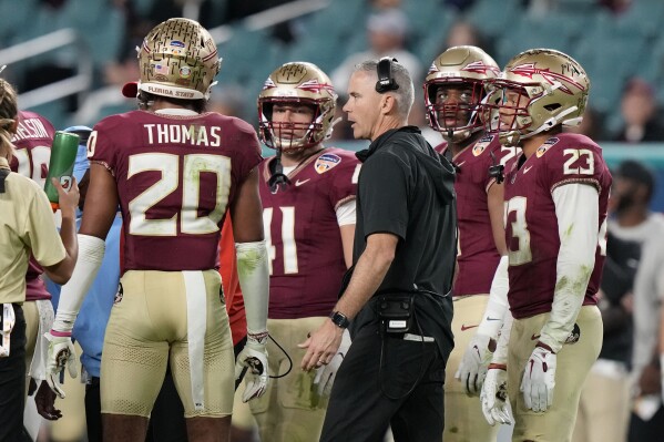 Florida State head coach Mike Norvell, center, talks with players on the field during the second half of the Orange Bowl NCAA college football game against Georgia, Saturday, Dec. 30, 2023, in Miami Gardens, Fla. (AP Photo/Lynne Sladky)