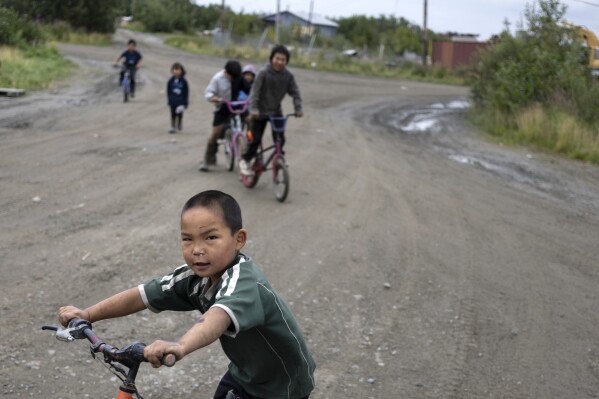 Wilson Noatak, 5, rides along Main Street on his bicycle with friends, Saturday, Aug. 19, 2023, in Akiachak, Alaska. (AP Photo/Tom Brenner)