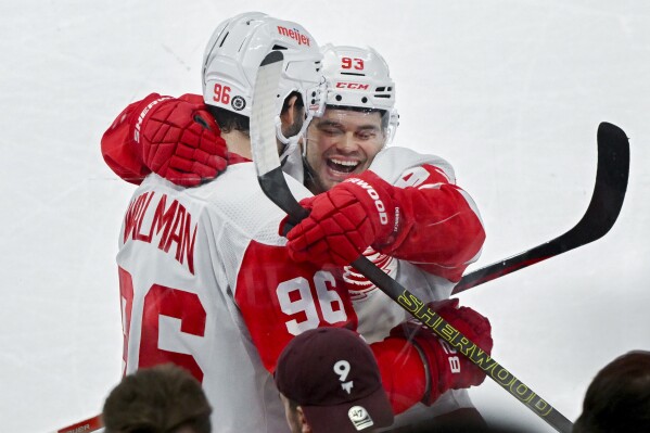 Detroit Red Wings' Jake Walman (96) celebrates with teammate Alex DeBrincat after scoring against the Montreal Canadiens during overtime of an NHL hockey game, Saturday, Dec. 2, 2023 in Montreal. (Graham Hughes/The Canadian Press via AP)