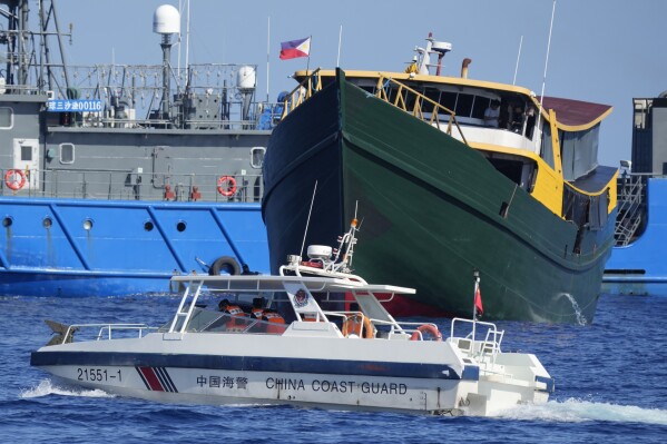 A Chinese coast guard boat moves near the Philippine resupply vessel Unaizah May 4 (in green) after it was hit by their water canon blast causing injuries to multiple crew members as they tried to enter the Second Thomas Shoal, locally known as Ayungin Shoal, in the disputed South China Sea Tuesday, March 5, 2024. Chinese and Philippine coast guard vessels collided in the disputed South China Sea and multiple Filipino crew members were injured in high-seas confrontations Tuesday as Southeast Asian leaders gathered for a summit that was expected to touch on Beijing's aggression at sea. (AP Photo/Aaron Favila)