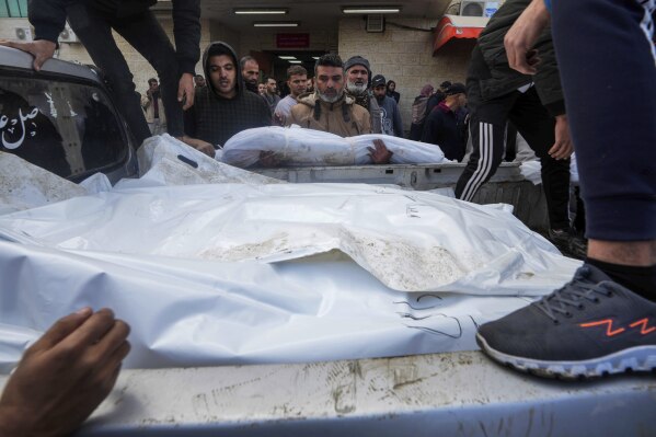 Palestinians load the bodies of their loved ones killed during Israeli bombardments on the Gaza Strip into a truck for burial at the Deir al Balah cemetery in the Gaza Strip, Monday, December 25, 2023. (AP Photo/Adel Hana )