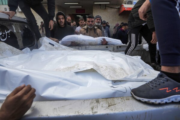 Palestinians load the bodies of their relatives killed in the Israeli bombardment of the Gaza Strip on a truck, to be buried at the cemetery in Deir al Balah, Gaza Strip, on Monday, Dec. 25, 2023. (AP Photo/Adel Hana)