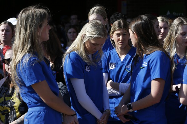 Augusta University College of Nursing students gather to mourn the loss of Laken Riley during a vigil for the nursing student at the Tate Plaza on the University of Georgia campus in Athens, Ga., Monday, Feb. 26, 2024. Riley, a nursing student at Augusta University's Athens campus, was found dead Thursday, Feb. 22, after a roommate reported she didn't return from a morning run in a wooded area of the UGA campus near its intramural fields. Students also gathered to pay tribute to a UGA student who committed suicide last week. (Joshua L. Jones/Athens Banner-Herald via AP)