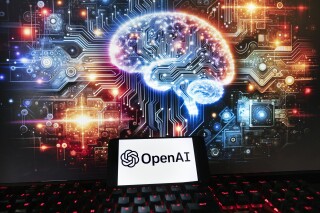 FILE - The OpenAI logo is seen displayed on a cell phone with an image on a computer monitor generated by ChatGPT's Dall-E text-to-image model, Friday, Dec. 8, 2023, in Boston. OpenAI will start using news content from News Corp. as part of a multiyear deal between the two companies. (AP Photo/Michael Dwyer, file)
