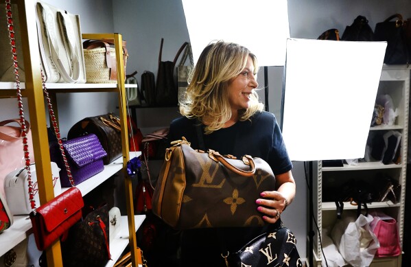 Deborah Mayer holds one of the luxury handbags she sells on TikTok, Wednesday, March 21, 2024, in Freehold, N.J. Mayer has sold new and pre-owned handbags and other designer goods out of her New Jersey home for 16 years. Early last year, TikTok recruited her business for the live component of TikTok Shop. (AP Photo/Noah K. Murray)