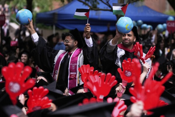 Two graduates wave Palestinian flags during commencement ceremonies at Harvard University, Thursday, May 29, 2025, in Cambridge, Mass. (AP Photo/Charles Krupa)