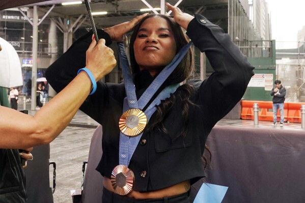 Two-time U.S. Olympic gymnast Jordan Chiles dons her medals as she prepares for photos outside the Nasdaq MarketSite, in New York's Times Square, Thursday, Aug. 8, 2024. (AP Photo/Richard Drew)