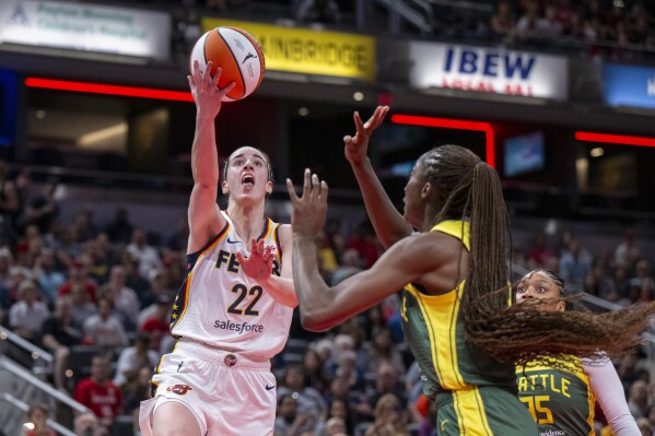 Indiana Fever guard Caitlin Clark (22) shoots against Seattle Storm center Ezi Magbegor during the first half of a WNBA basketball game Thursday, May 30, 2024, in Indianapolis. (AP Photo/Doug McSchooler)