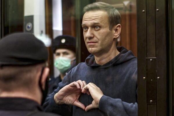 FILE - In this handout photo taken from a footage provided by Moscow City Court in Feb. 2, 2021, Russian opposition leader Alexei Navalny shows the heart symbol from the cage, during a hearing at the City Court in Moscow, Russia. Imprisoned Russian opposition leader Alexei Navalny has been awarded the European Union's top human rights prize, in a clear slap at President Vladimir Putin. In awarding the Sakharov Prize to Navalny, the European Parliament praised his "immense personal bravery." The 45-year-old activist was poisoned with a nerve agent last year and promptly arrested upon his return to Moscow from treatment in Germany and later imprisoned. (Moscow City Court via AP, File)