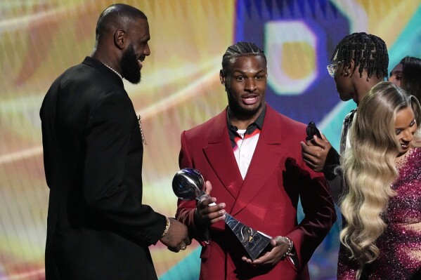 Los Angeles Lakers' LeBron James, left, accepts the award for best record-breaking performance from his sons, Bronny James, center, and Bryce James, at the ESPY awards July 12, 2023, in Los Angeles. Bronny James was hospitalized in stable condition Tuesday, July 25, 2023, a day after going into cardiac arrest while participating in a practice at the University of Southern California, a family spokesman said. (AP Photo/Mark J. Terrill)
