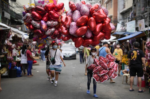 FILE - Women sell heart-shaped balloons at a flower market in Manila, Philippines on Monday, Feb. 13, 2023. Valentine's Day is one of those Hallmark holidays that haters call 鈥渇orced," too commercialized and downright expensive to pull off if expectations are to be met. (AP Photo/Aaron Favila, File)