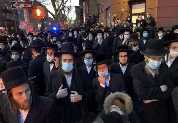 FILE- In this April 28, 2020 file photo, hundreds of mourners gather in the Brooklyn borough of New York, to observe a funeral for Rabbi Chaim Mertz, a Hasidic Orthodox leader whose death was reportedly tied to the coronavirus. On Friday, June 26, 2020, a federal judge in New York blocked the state from enforcing coronavirus restrictions limiting indoor religious gatherings to 25% capacity when other types of gatherings are limited to 50%. Restrictions limiting the number of people who can attend outdoor religious gatherings will also be lifted by the injunction. (Peter Gerber via AP, File)