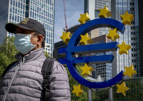 A man walks by the Euro sculpture in front of the old the European Central Bank in Frankfurt, Germany, Tuesday, May 5, 2020. Germany's Constitutional Court has ruled that the country's central bank must stop participating in a key European Central Bank stimulus program but gave the ECB time to demonstrate that the stimulus program is needed and appropriate. (AP Photo/Michael Probst)