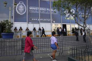 Los peatones pasan frente a la Fiscalía donde la presidenta peruana Dina Boluarte llegó a testificar en Lima, Perú, el viernes 5 de abril de 2024. (AP Foto/Martín Mejía)
