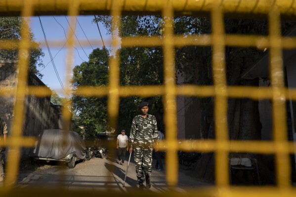 A security person stands guard outside the office of Delhi Police's Special Cell in New Delhi, India, Tuesday, Oct. 3, 2023. Indian police raided the offices of a news website that’s under investigation for allegedly receiving funds from China, as well as the homes of several of its journalists, the latest in a series of investigations into the finances of independent media in India. (AP Photo/Altaf Qadri)