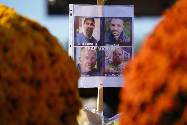 At a makeshift memorial shows images of members of the deaf community who were killed in the mass shooting at Schemengees Bar and Grille in Lewiston, Maine, Saturday, Oct. 28, 2023. (AP Photo/Matt Rourke)
