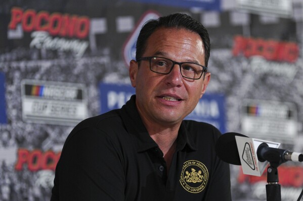 Pennsylvania Gov. Josh Shapiro talks to the media prior to a NASCAR Cup Series auto race at Pocono Raceway, Sunday, June 22, 2025, in Long Pond, Pa. (AP Photo/Derik Hamilton)