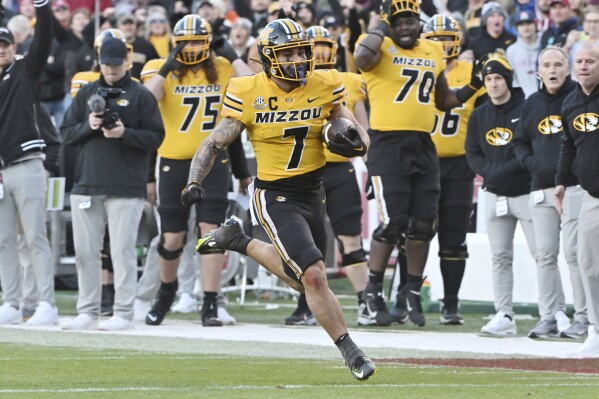 FILE - Missouri running back Cody Schrader (7) runs the ball against Arkansas during an NCAA college football game Friday, Nov. 24, 2023, in Fayetteville, Ark. Ninth-ranked Missouri is in its first New Year’s Six game during the four-team College Football Playoff era against seventh-ranked Ohio State in the Cotton Bowl. (AP Photo/Michael Woods, File)