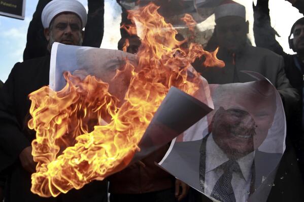 Palestinians burn posters of Israeli Prime Minister Benjamin Netanyahu and U.S. President Donald Trump, during a protest against the U.S. decision to recognize Jerusalem as Israel's capital, in Gaza City Thursday, Dec. 7, 2017. (AP Photo/ Khalil Hamra)