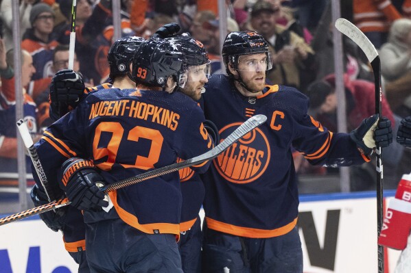 Edmonton Oilers' Ryan Nugent-Hopkins (93), Leon Draisaitl (29) and Connor McDavid (97) celebrate after a goal against the Seattle Kraken during second-period NHL hockey game action in Edmonton, Alberta, Thursday, Jan. 18, 2024. (Jason Franson/The Canadian Press via AP)