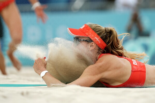Switzerland's Nina Brunner lands in the sand after diving for a shot in a beach volleyball match against France at the 2024 Summer Olympics, Saturday, Aug. 3, 2024, in Paris, France. (AP Photo/Robert F. Bukaty)
