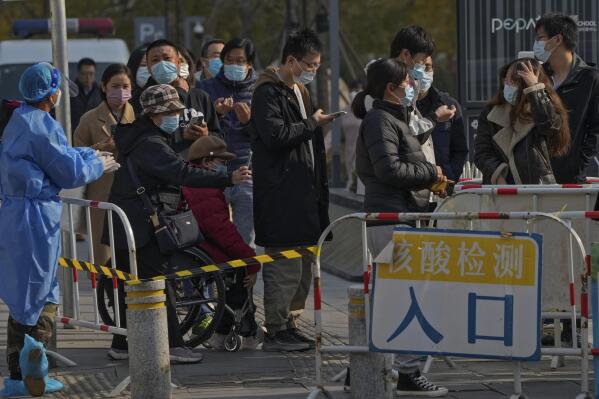 People use their smartphones to scan the health check QR codes before getting their routine COVID-19 throat swabs at a coronavirus testing site in Beijing, Tuesday, Nov. 8, 2022. Police in northeastern China say seven people have been arrested following a clash between residents and authorities enforcing COVID-19 quarantine restrictions. (AP Photo/Andy Wong)