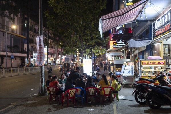 2024 年 1 月 27 日星期六，越南胡志明市，一群人在一家餐馆外的人行道上分享用大米制成的菜肴。越南是世界第三大大米出口国，也是越南文化的重要组成部分在湄公河三角洲地区尤为明显。  （美联社照片/Jae C. Hong）