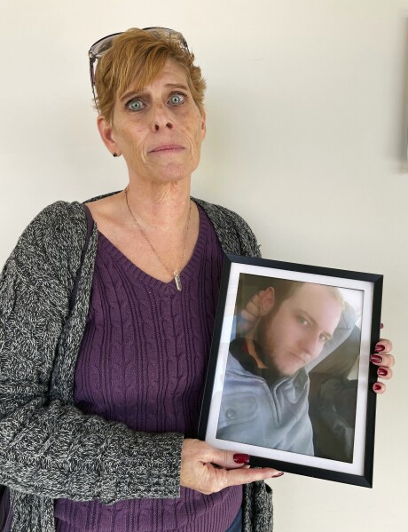 Heather DeWolf holds up a photo of her late son, Zach DeWolf, who died in 2020 at age 33, Tuesday, Dec. 5, 2023, in Colorado Springs, Colo. Colorado's Return to Nature Funeral Home, where 190 decaying bodies were found in October, handled his remains. Now, DeWolf fears the ashes she received from the funeral home are not her son's and that his body was instead part of the grim discovery. (AP Photo/Jesse Bedayn)