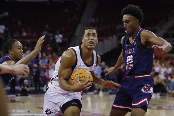 San Diego State forward Jaedon LeDee drives against Fresno State's Leo Colimerio, right, during the first half of an NCAA college basketball game in Fresno, Calif., Saturday, Feb. 24, 2024. (AP Photo/Gary Kazanjian)