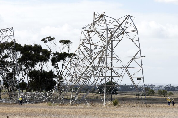 Workers inspect damaged electricity transmission towers on the outskirts of Melbourne, Australia, Wednesday, Feb. 14, 2024. Powerful winds have killed at least one person and brought widespread destruction across Australia's second-most populous state, leaving 530,000 homes and businesses without power and fanning fires that razed homes and left five firefighters injured, officials say. (Con Chronis/AAP Image via AP)